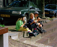 840043 Afbeelding van drie jeugdige skeeleraars, die een ijsje van IJssalon Il Mulino (Adelaarstraat 4) eten op de kade ...